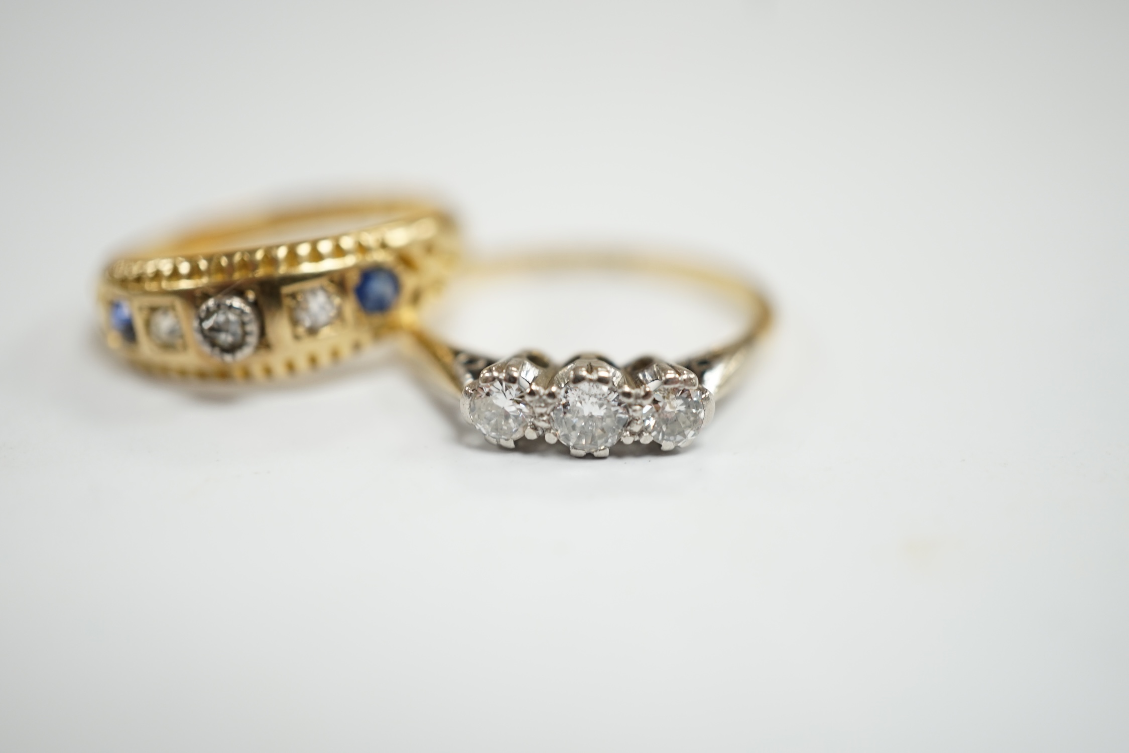 An 18ct, plat and three stone diamond set ring, size K and a late Victorian 18ct gold three stone diamond and two stone sapphire set ring, size K, gross weight 4.1 grams.